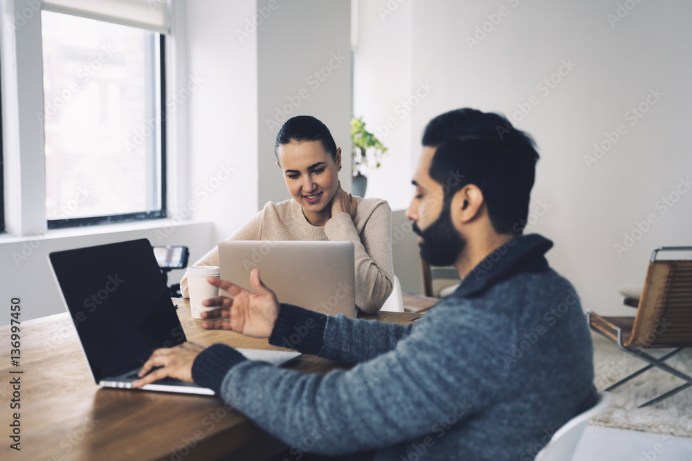 Business people using laptop computers while sitting at desk in office Business people using laptop computers while sitting at desk in office