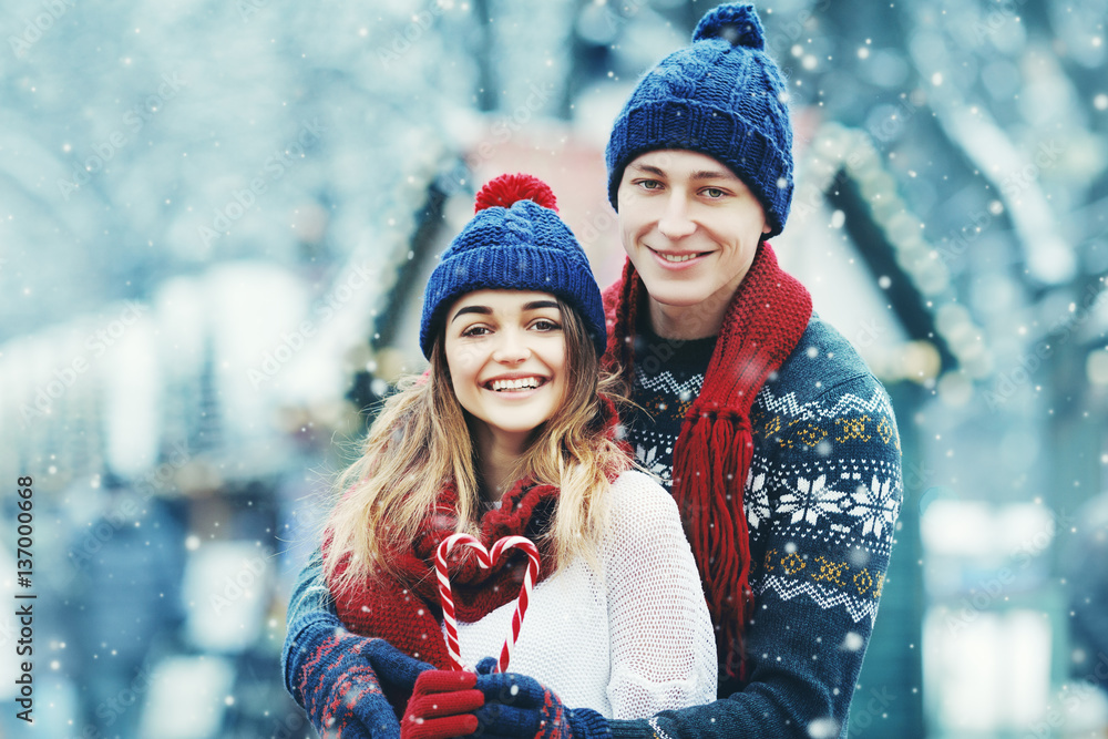 beautiful diverse couple in fashionable winter clothes hugging warmly and  looking at camera Stock Photo by LightFieldStudios
