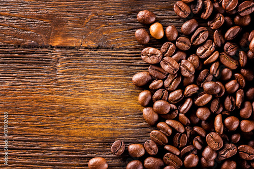 Macro image of roasted coffee beans at brown textured wooden boa