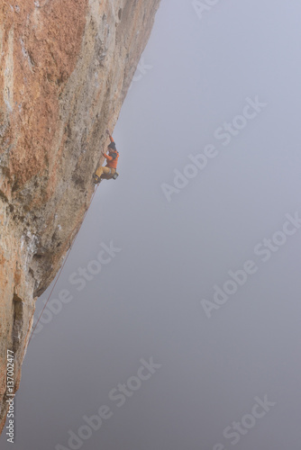 Outdoor sport. Rock climber ascending a challenging cliff. Extreme sport climbing. 