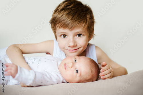 portrait of cute happy siblings. young boy holding his infant baby