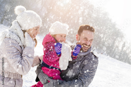 Young Couple with Kid Enjoying On Winter Day While Falling Snow