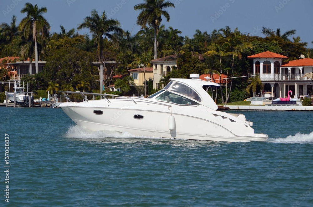 Luxury cabin cruiser on the florida intra-coastal waterway with luxury island homes in the background.