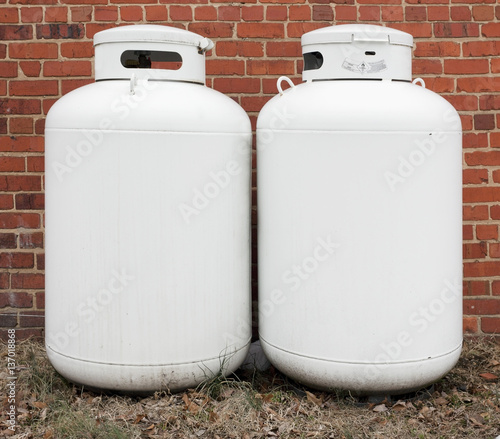 Two home propane tanks against brick wall.  photo