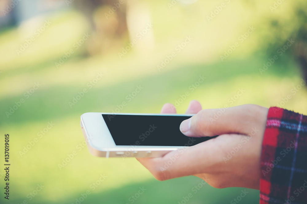 Young woman using a smartphone outdoors at park. Young woman using a smartphone outdoors at park.