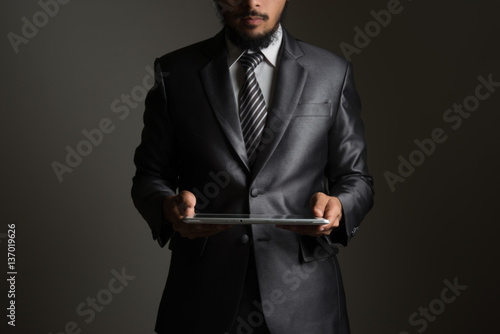 Business man holding tablet isolated on grey.