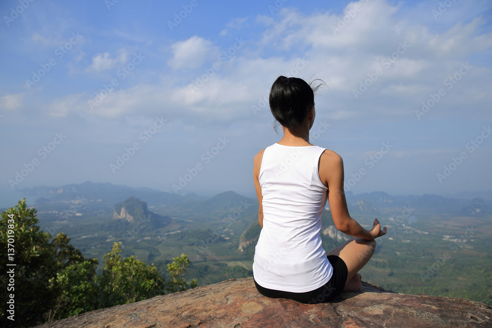 young woman practice yoga  at mountain peak