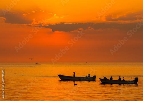fishing boats silhouetted against a golden sunrise Sea of Cortez 