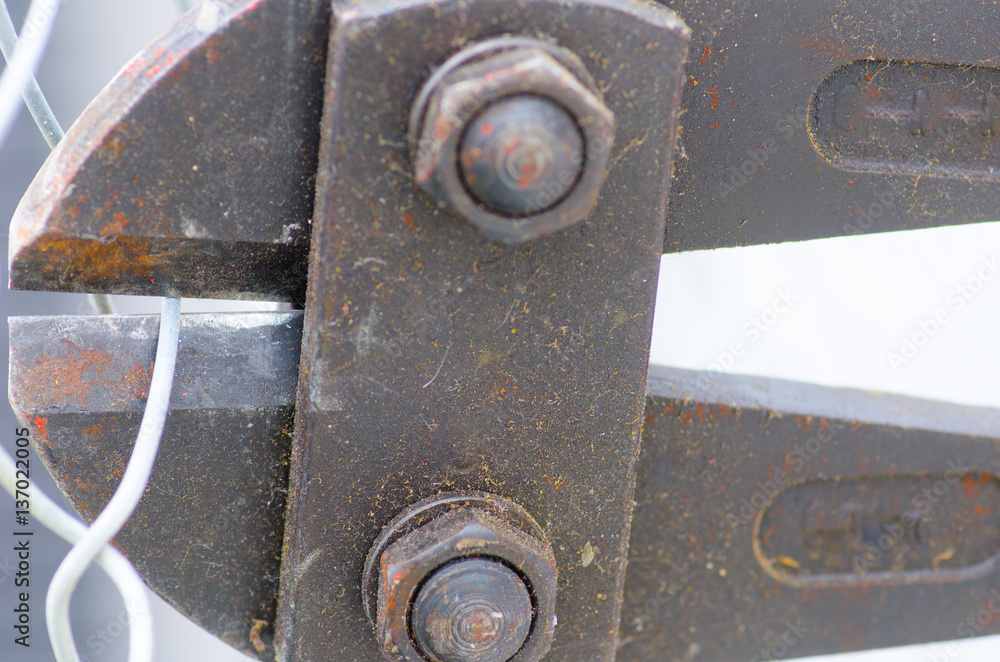 Dirty Bolt cutter clipping fence close up