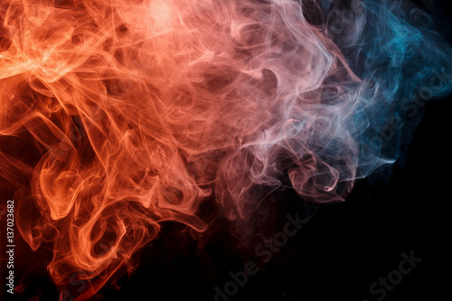 Abstract smoke Weipa. Personal vaporizers fragrant steam. The concept of alternative non-nicotine smoking. Orange turquise smoke on black background. E-cigarette. Evaporator. Taking Close-up. Vaping.