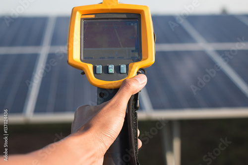 engineer or electrician working on maintenance equipment at industry solar power; engineer using thermal imager to check temperature heat of solar panel 