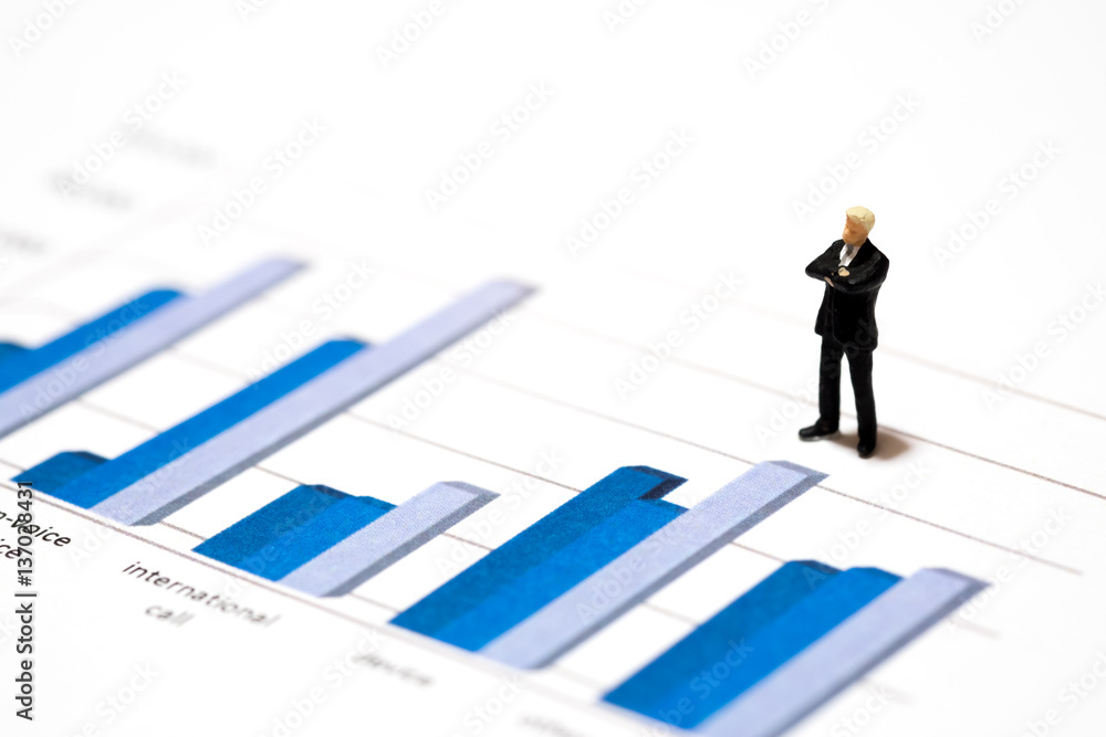 Miniature figures businessmen standing on a graph chart financial analysis review document with the team. Miniature figures businessmen standing on a graph chart financial analysis review document with the team.