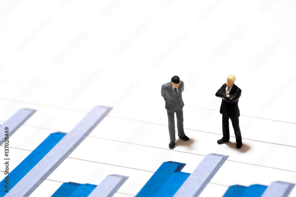 Miniature figures businessmen standing on a graph chart financia Miniature figures businessmen standing on a graph chart financia