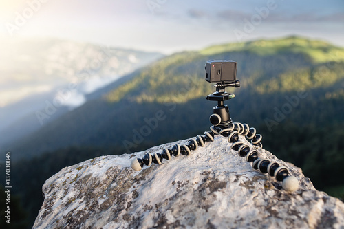 Closeup of action camera on flexible tripod, standing on the roc