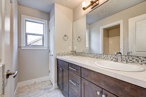 New light bathroom interior with double sink dark wood bathroom vanity accented with mosaic backsplash. Northwest, USA
