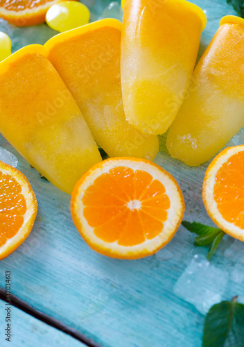 home made orange popsicles on turquoise wooden surface