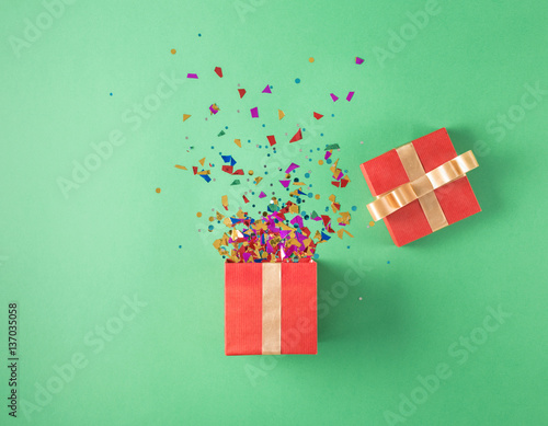 Open red gift box with various party confetti photo