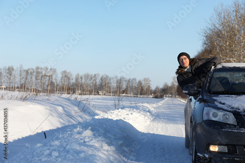 man looks out the car window at the snow-covered road