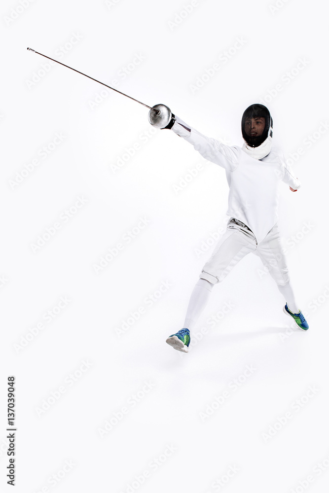 Man wearing fencing suit practicing with sword against gray Man wearing fencing suit practicing with sword against gray