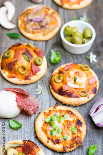 Different Types of Pizza with Ingredients on Wood Background
