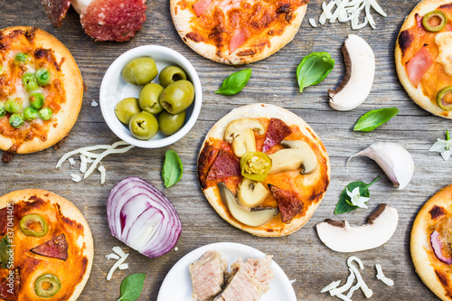 Top View of Different Types of Small Pizza with Ingredients on Wooden Background