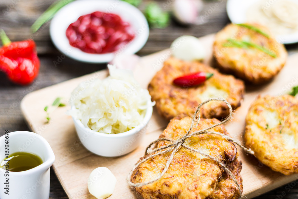 Fresh Potato Pancakes on Breadboard with Ingredients on Wooden Background Fresh Potato Pancakes on Breadboard with Ingredients on Wooden Background