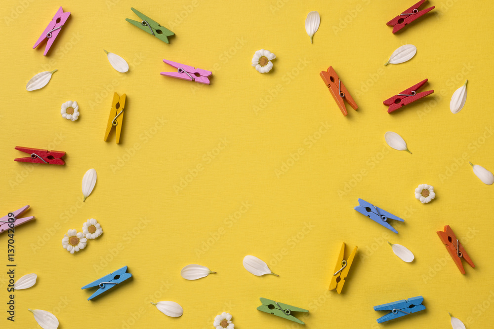 Spring or summer background with frame space for text: chamomiles, petals, many bright multicolored clothespins. Top view. Flat lay. Spring or summer background with frame space for text: chamomiles, petals, many bright multicolored clothespins. Top view. Flat lay.
