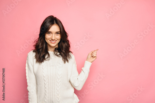 Cute young woman points a finger away photo