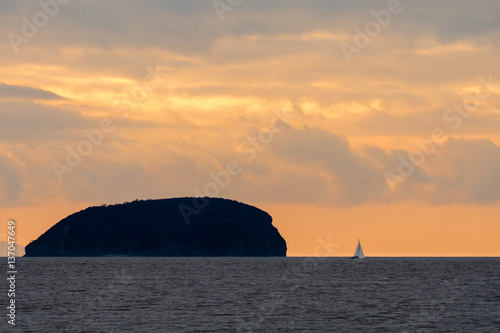 Sunset behind Steep Holm Island in the Bristol Channel, with yacht. Spectacular sky and clouds seen from Weston-super-Mare in Somerset, UK, at high tide