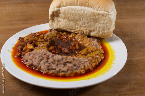 A plate of mashed beans, red palm oil stew and bread photo