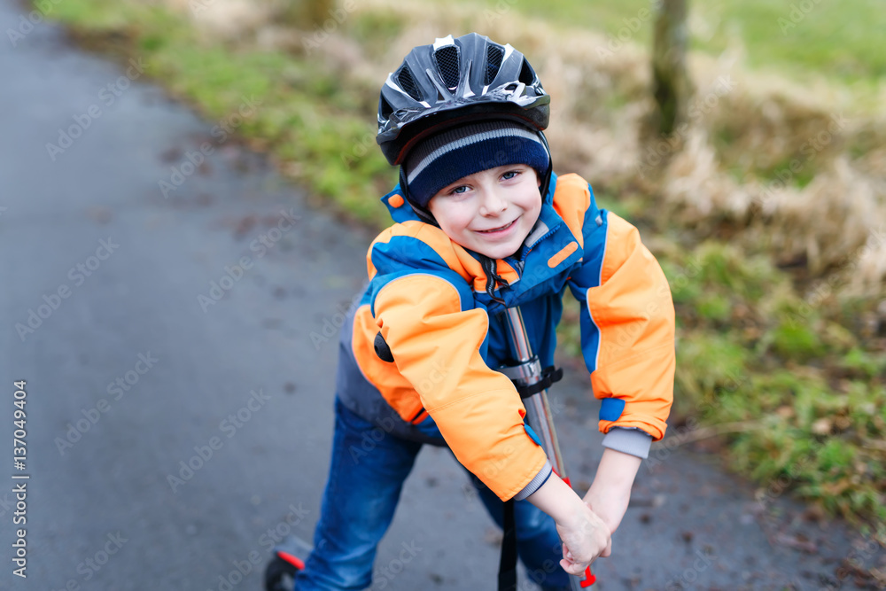 Cute preschool kid boy riding on scooter in park Cute preschool kid boy riding on scooter in park