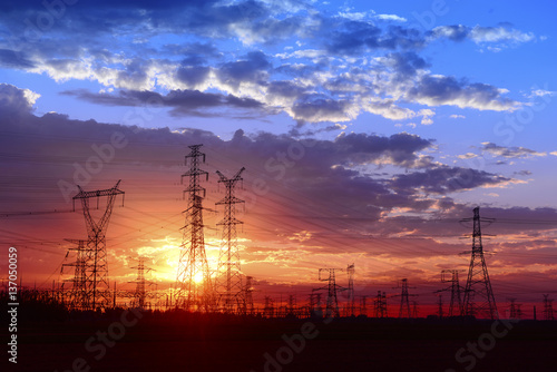 Many high voltage towers under the sunset