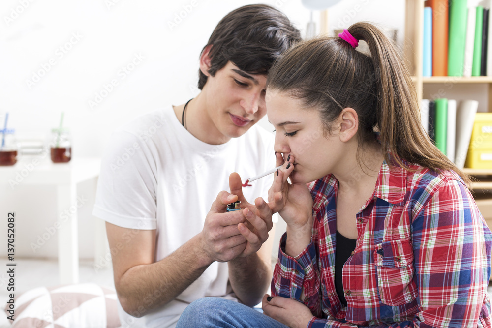 Teenage couple smoking. Boy lighting a cigarette to a girl Stock Photo