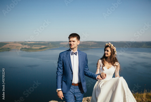 The brides hold hands on the background of river © myronovychoksana