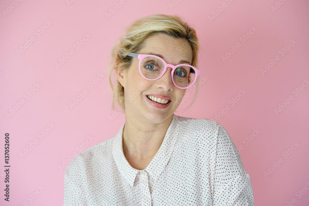 Portrait of blond woman with pink eyeglasses on pink background