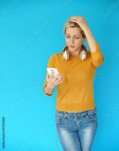 Blond woman with eyeglasses using smartphone and headphones, isolated