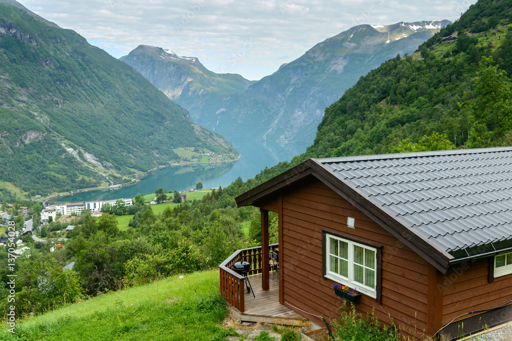 Beautiful view at fiord in a summer day with wooden cabin at foreground, Norway