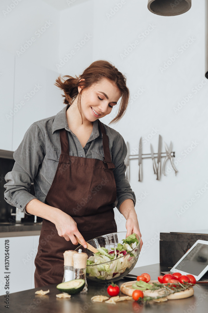 Pretty woman cooking in kitchen using tablet