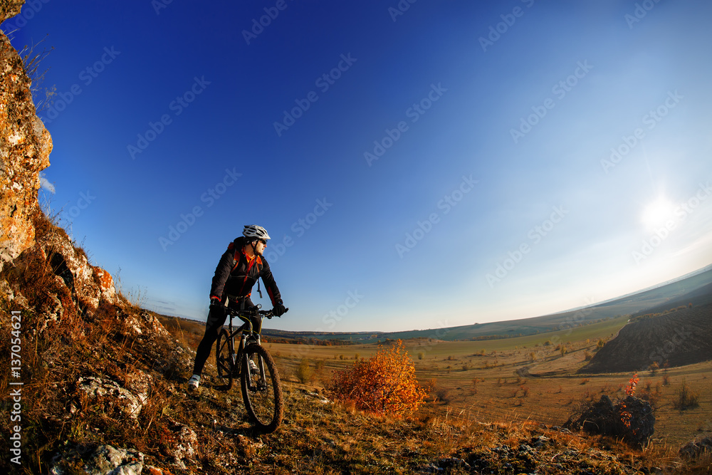 Fototapeta premium Wide angle view of a cyclist riding a bike on a nature trail in the mountains.