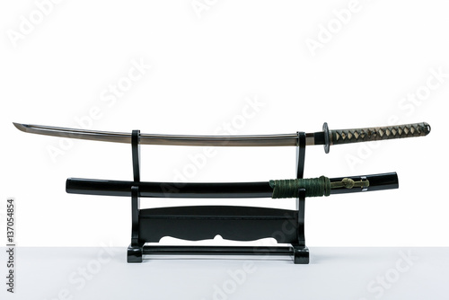 Japanese iaido sword in black wooden stand and white background. Still life studio shot of Japanese sword.