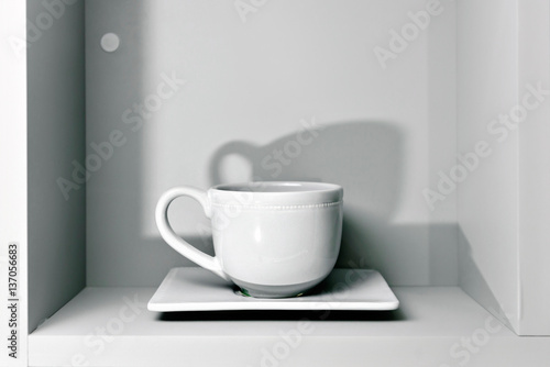 one white Cup and saucer on the shelf