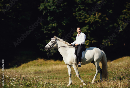 The seriously groom riding a horse