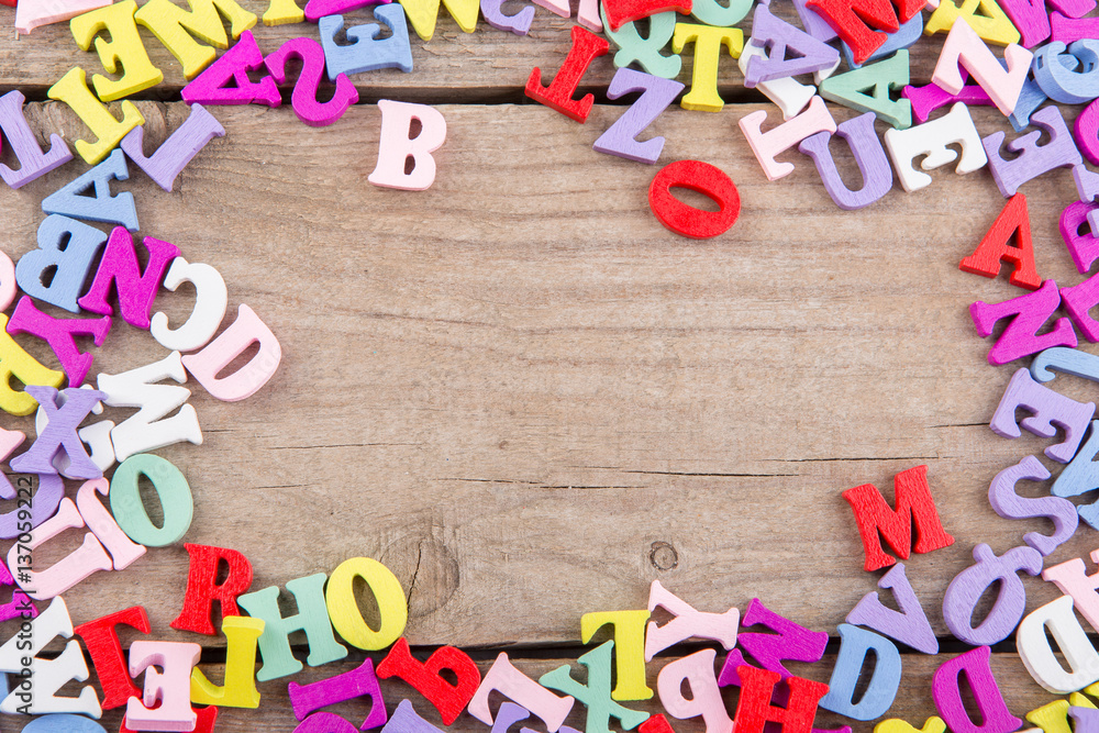Frame of colored wooden letters on a wooden background Frame of colored wooden letters on a wooden background