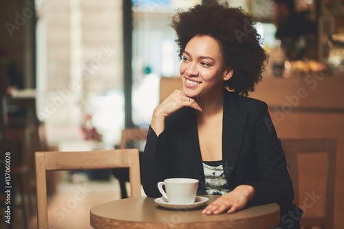 Mixed race, African American woman drinking coffee in cafe