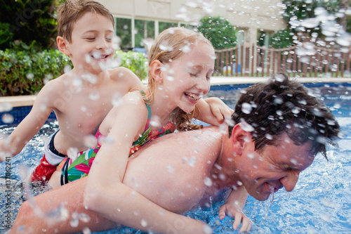 Father with children having fun in swimming pool.