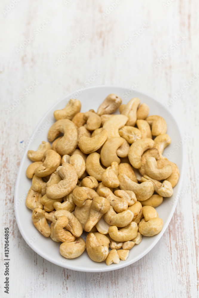 cashew on white dish on wooden background cashew on white dish on wooden background