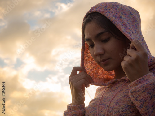 Asian woman wearing hood, sutset sky background photo