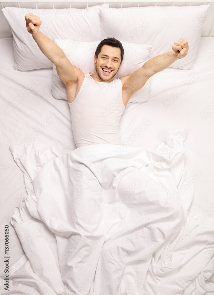 Handsome guy stretching himself in bed Handsome guy stretching himself in bed