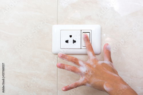 Wet hand of children trun on electric switch. Concept of do not use electricity with wet hand and safety of children.