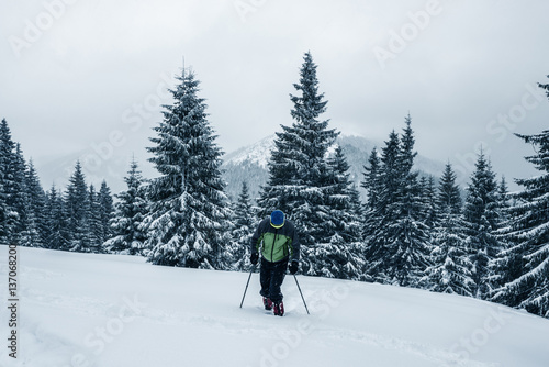 Traveler man climbs up the slope in deep snow